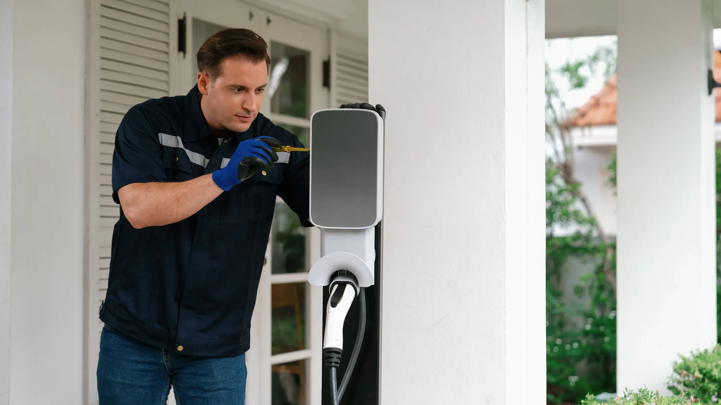 Electric vehicle technician working on a charging station, using a screwdriver.