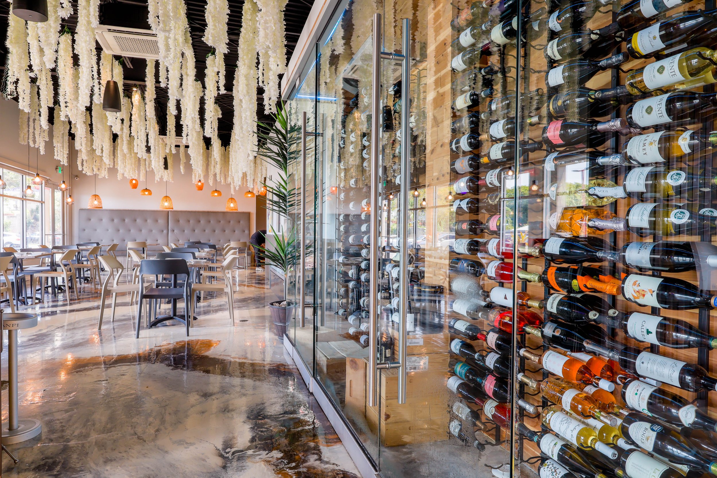 Aerial view of a coastal residential area with forested and grassy land, showing a highlighted orange plot of land near the shoreline, with houses and infrastructure surrounding it.