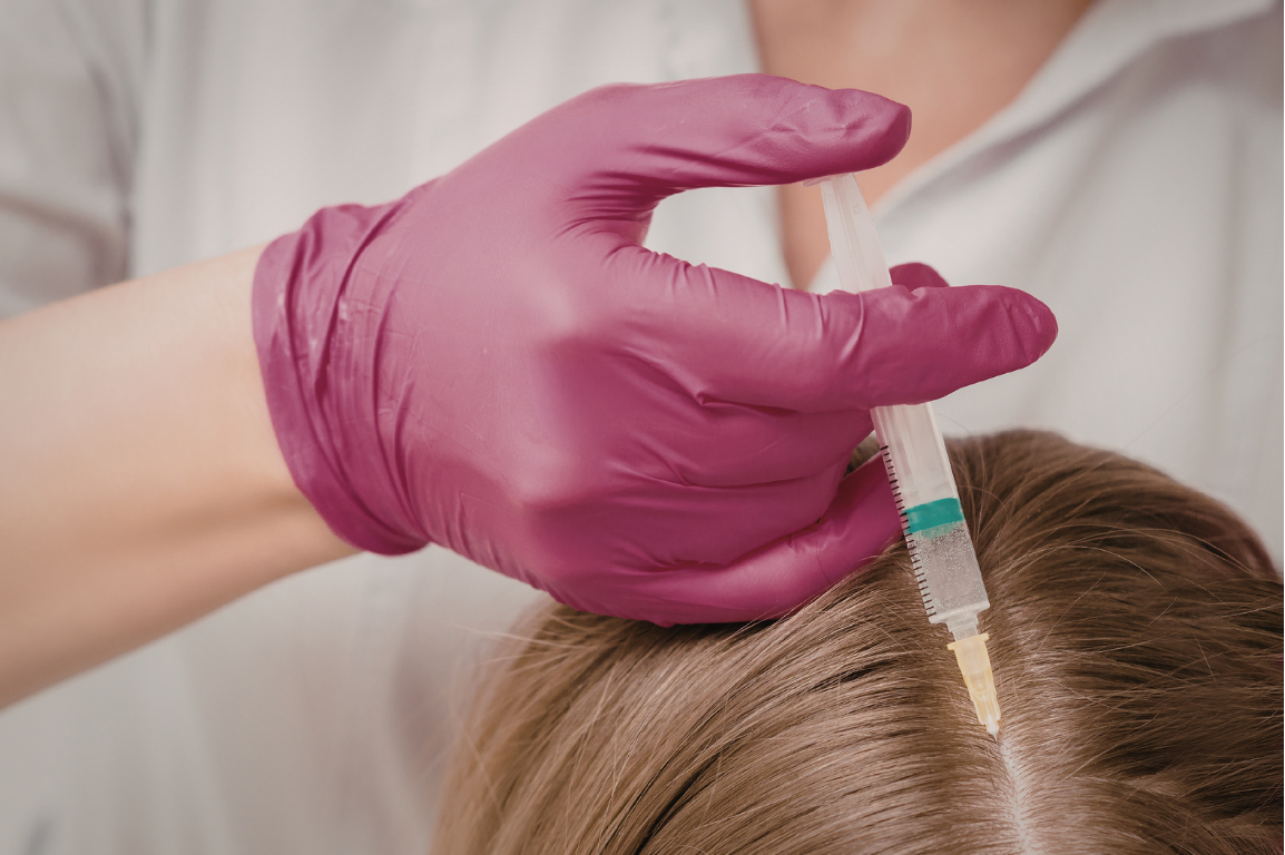 Medical professional wearing pink gloves administering a vaccination or injection to a person's scalp with a syringe.