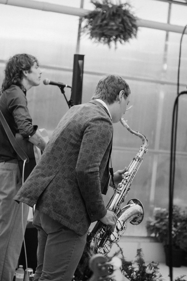 A man playing a saxophone and a woman singing into a microphone in an indoor setting.