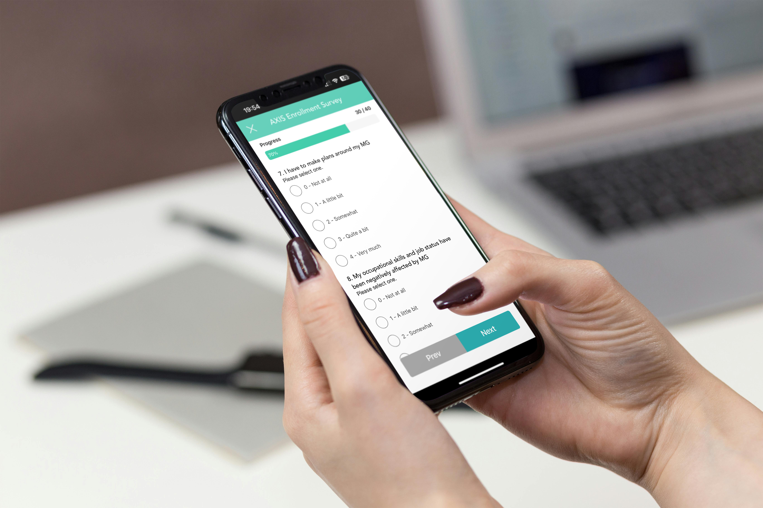 A person holding a smartphone with an AXIS survey on the screen; background shows a laptop, pen, and notebook.