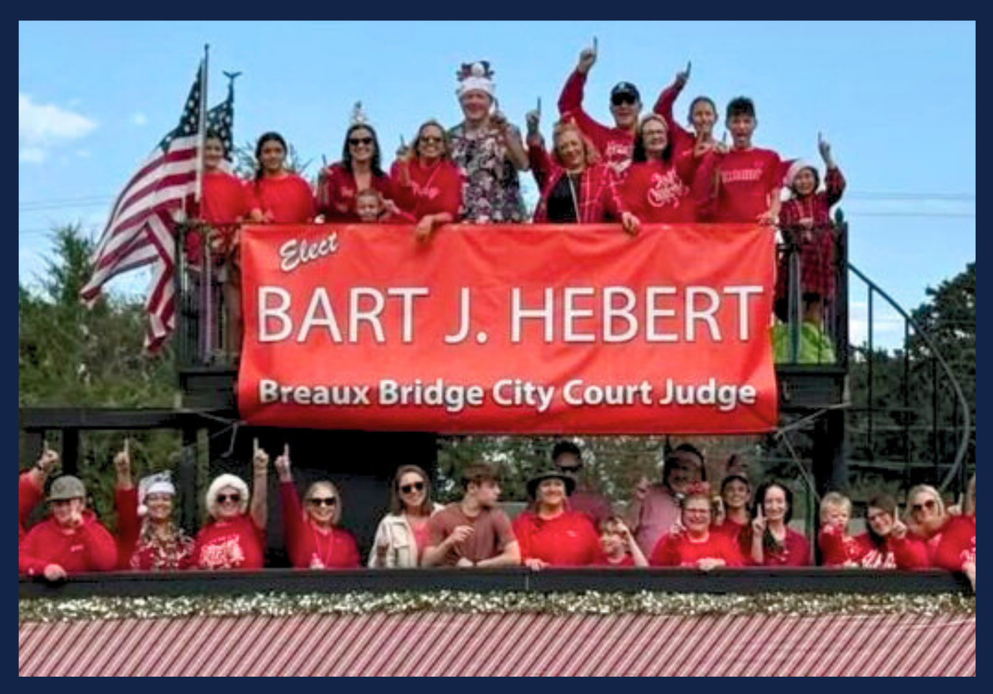 Friends, family, voters, and community supporters celebrate on a parade float decorated in support of Bart Hebert for City Court Judge. Float riders are holding an 'Elect Bart J. Hebert, Breaux Bridge City Court Judge' banner with an American flag.