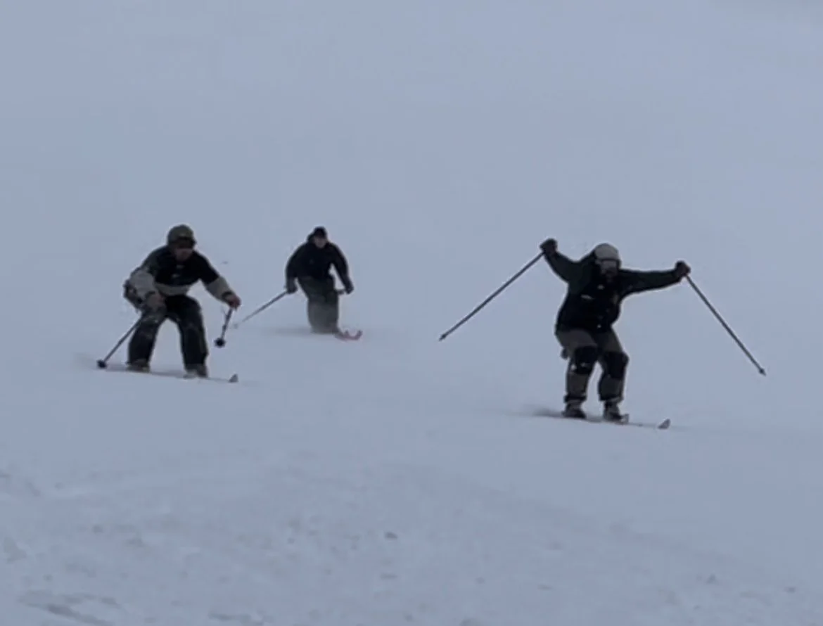 Three people skiing on snow-covered terrain during daytime.