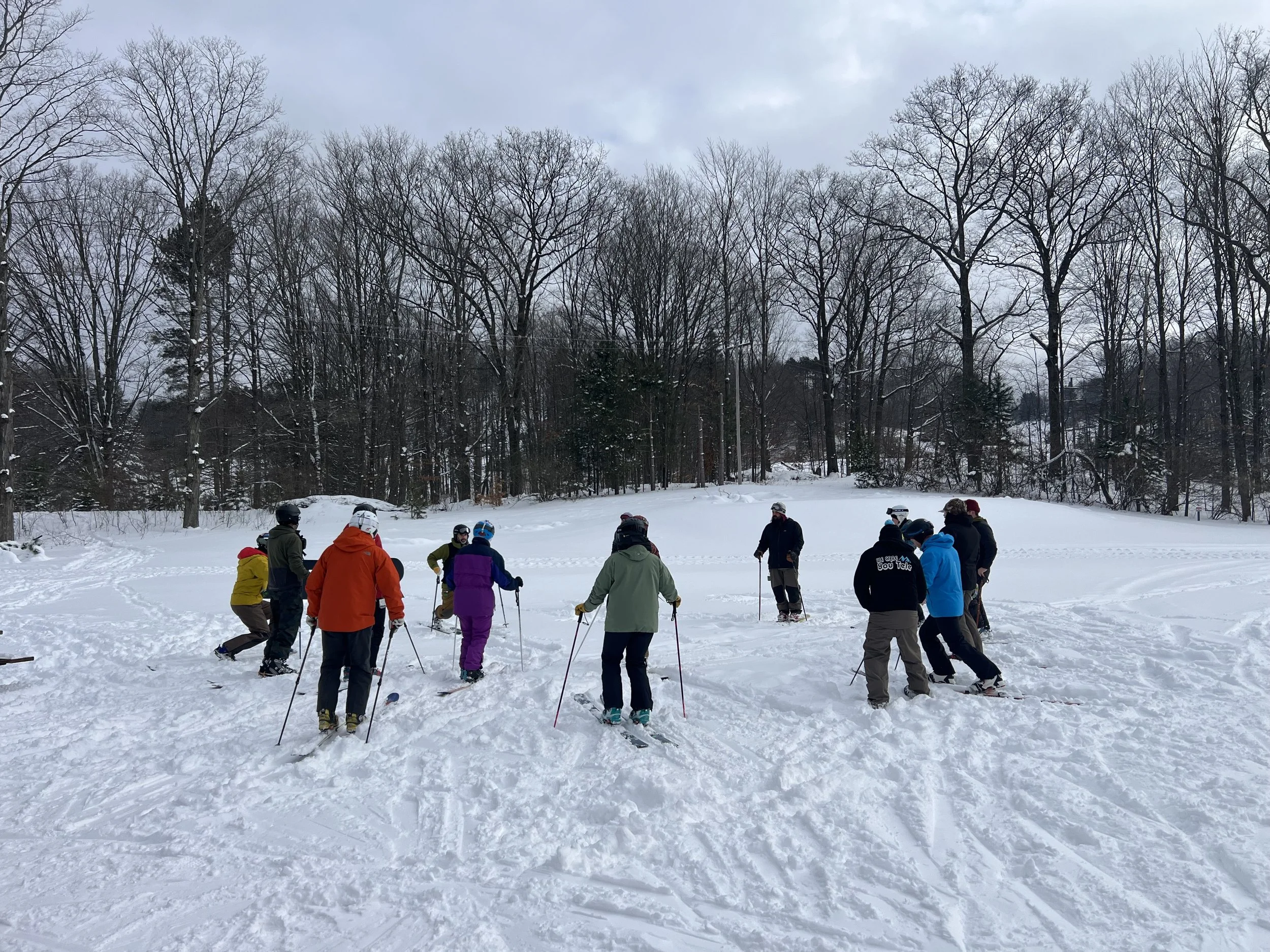 Group of people snowshoeing on a snowy field with a forest in the background.