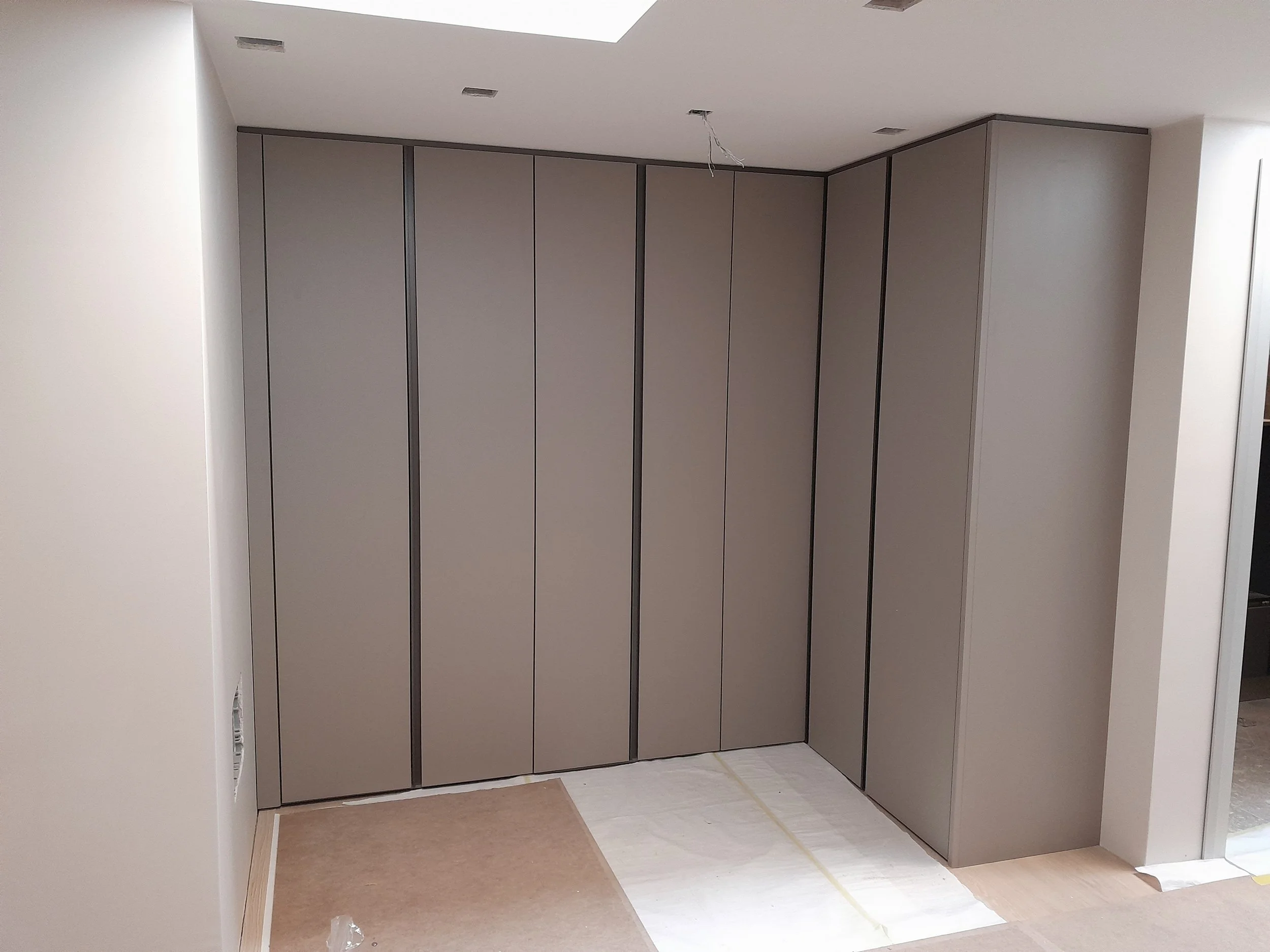 Armadi a muro in fase di installazione in una stanza, con pavimento coperto da protezioni temporanee