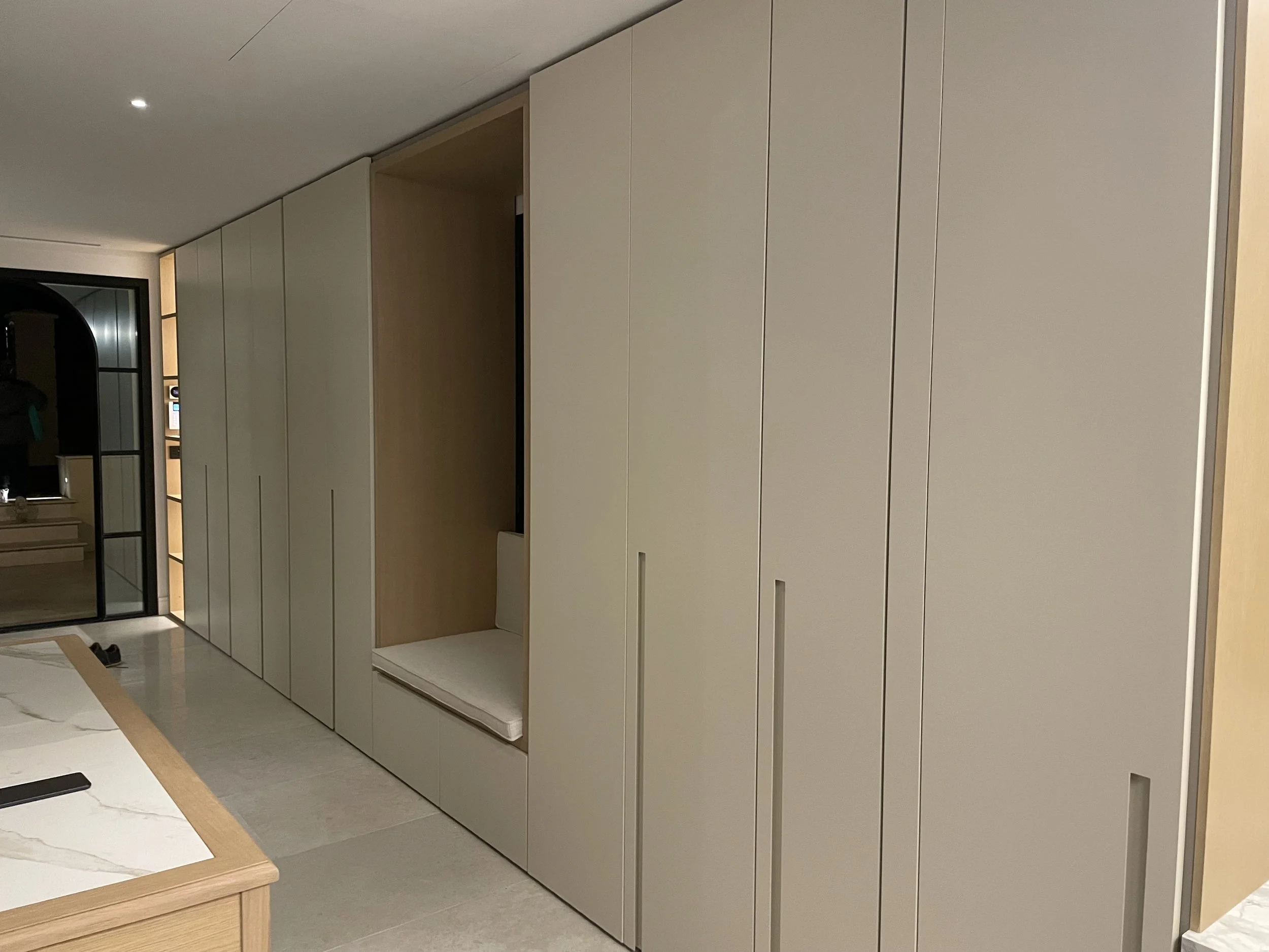 Armadi moderni in legno chiaro con ante scorrevoli e una nicchia con seduta