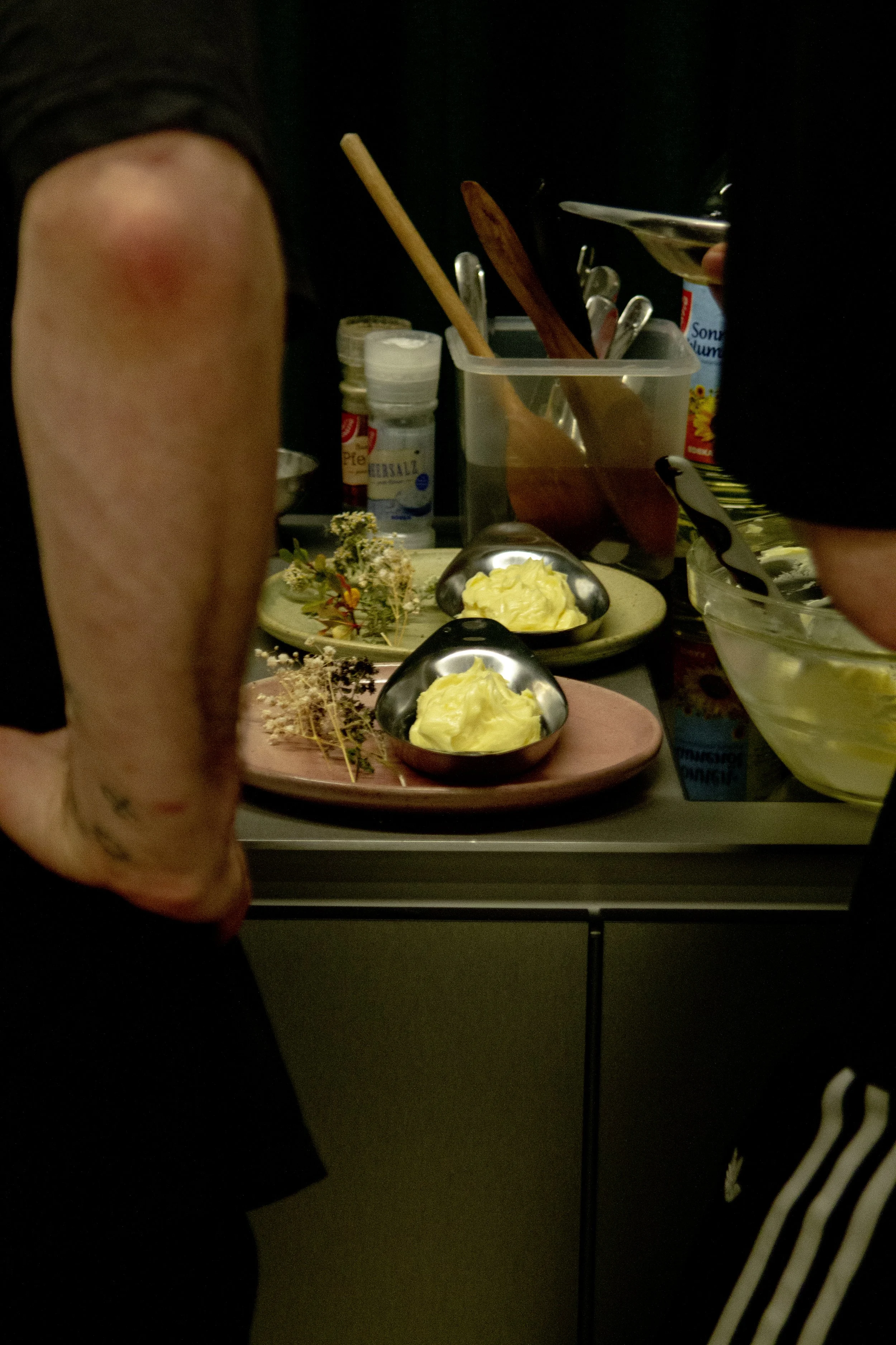 A person preparing or cooking in a kitchen with bowls of yellow ingredients and various kitchen utensils on the counter.