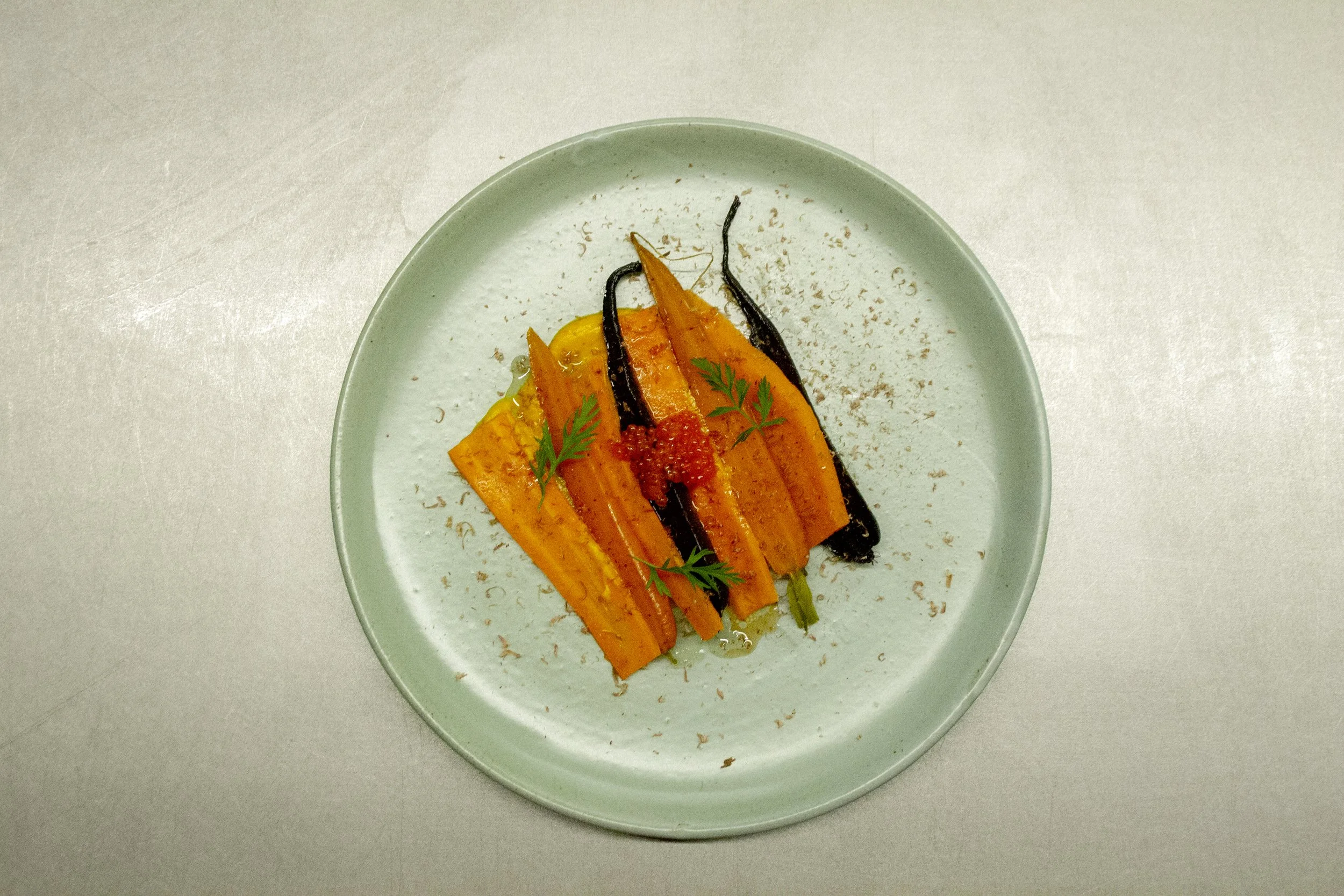 Roasted carrots garnished with herbs on a white ceramic plate