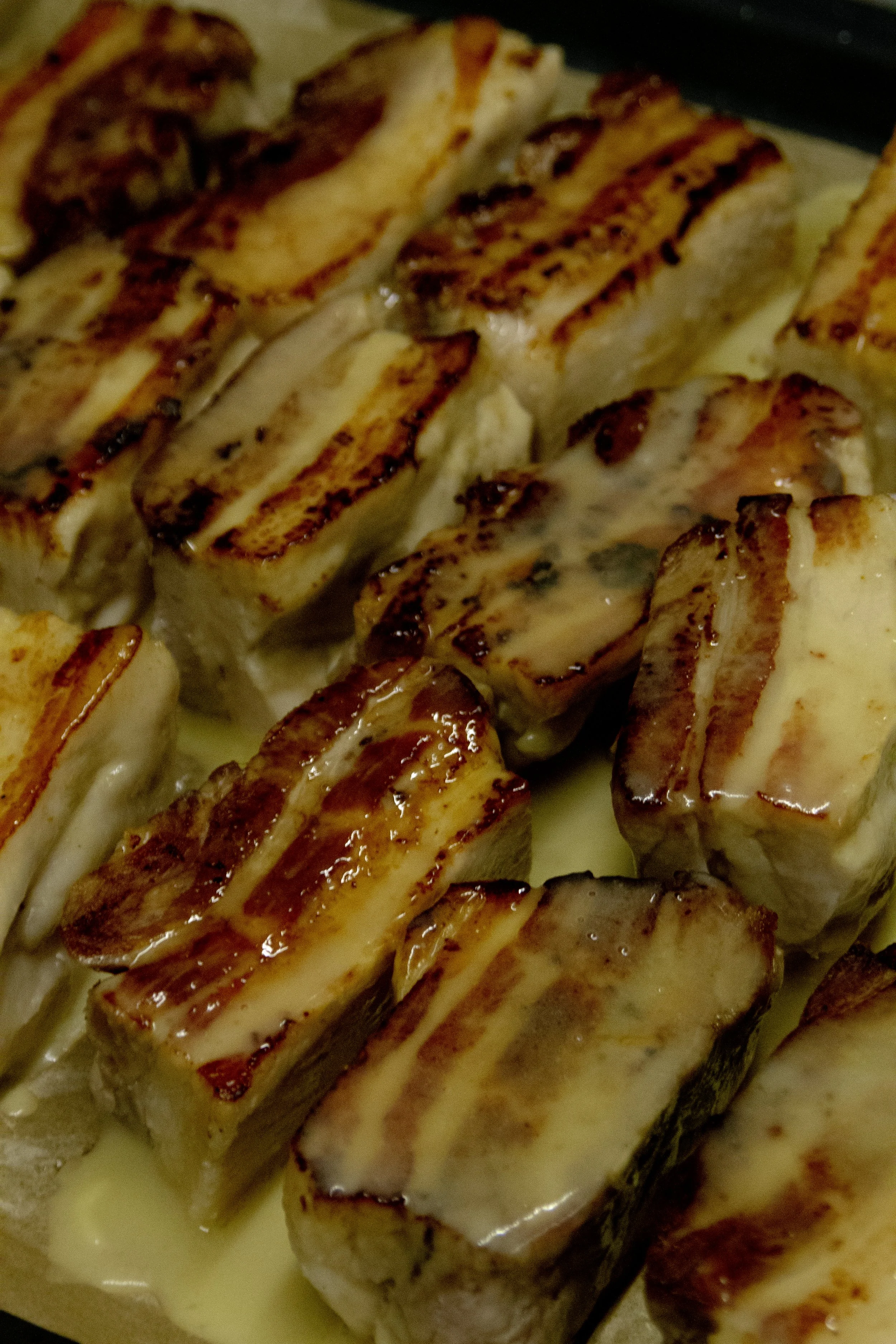 Close-up of grilled chicken breasts with grill marks, topped with a creamy sauce.
