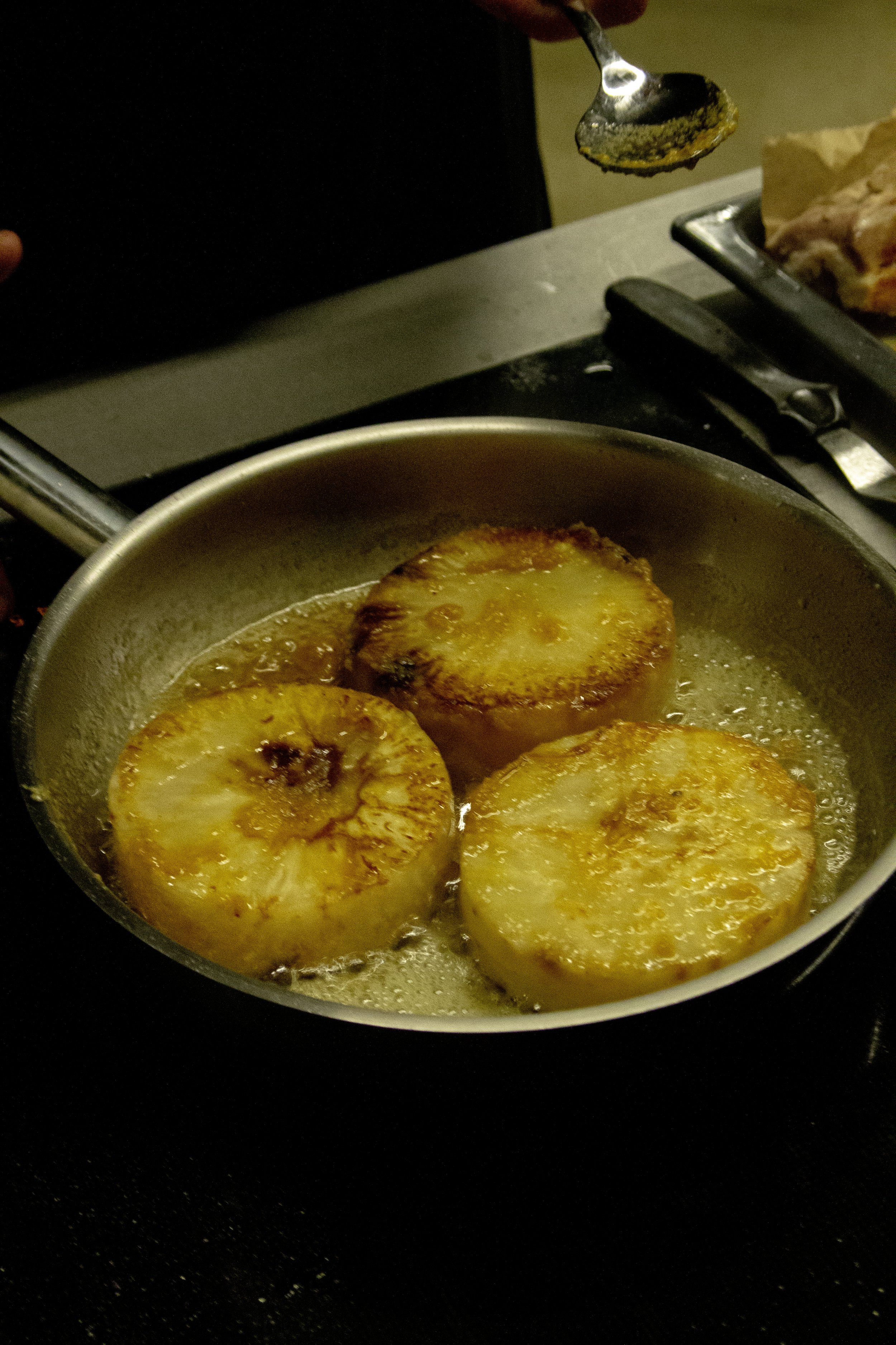 Slices of fried plantains cooking in a pan with butter.