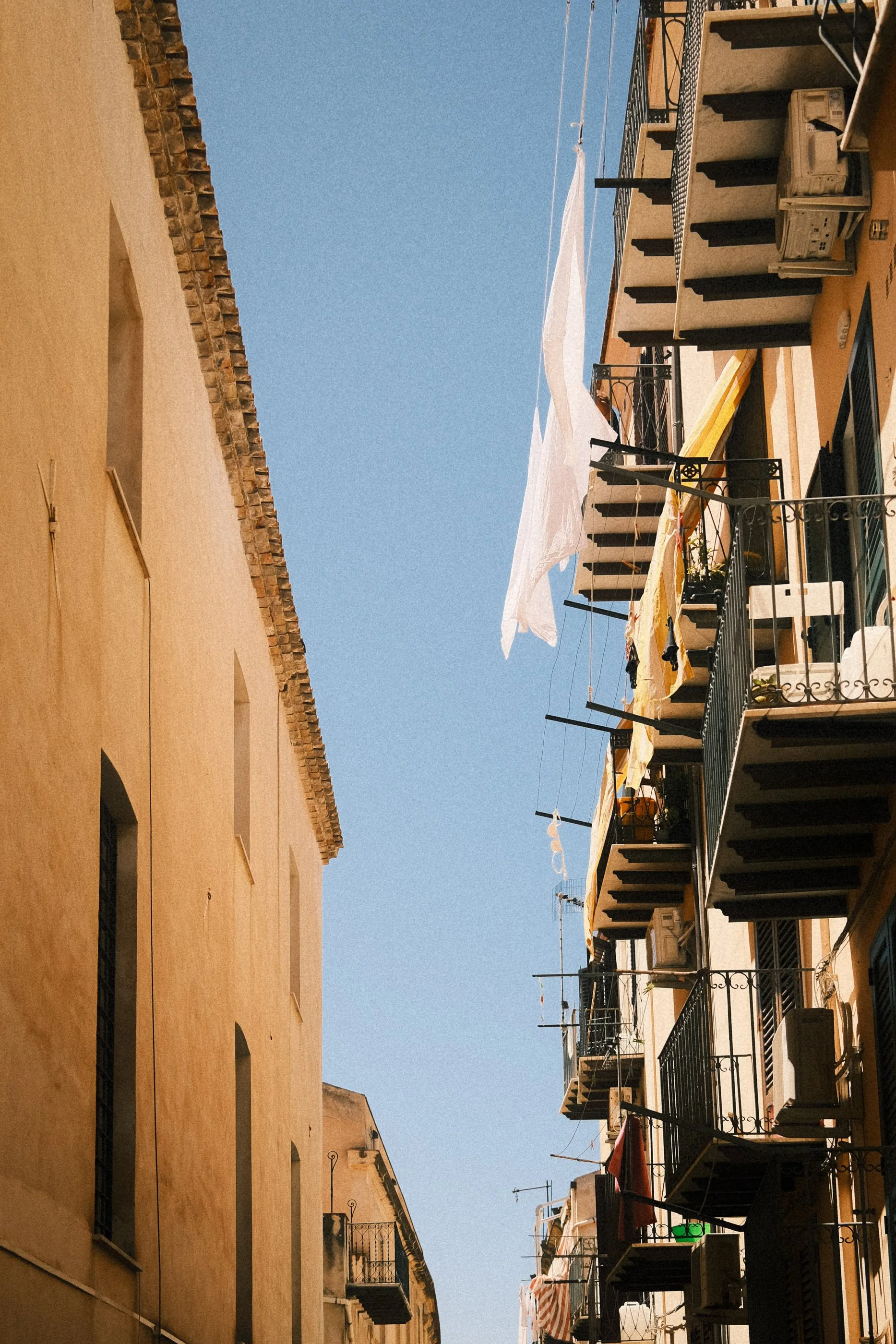 View of neighboring apartment buildings with balconies, laundry hanging, and a clear blue sky.