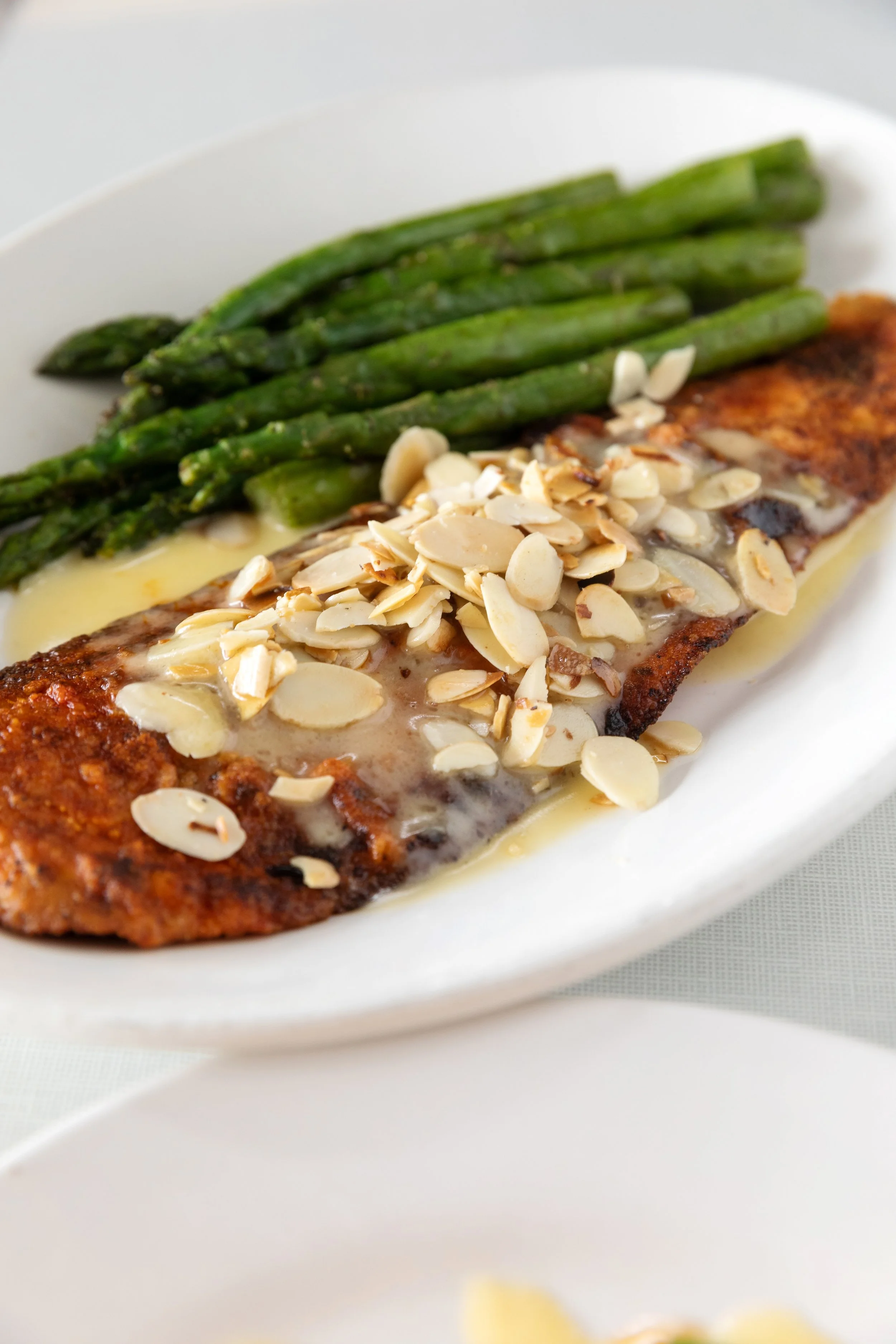 Grilled fish fillet topped with sliced toasted almonds served with asparagus spears.