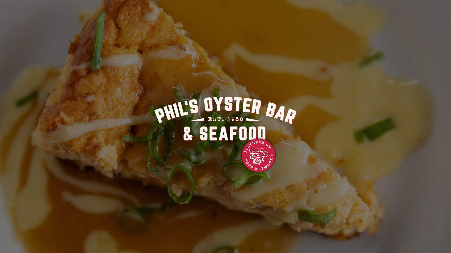 Phil's Oyster Bar & Seafood signature Crawfish Cheesecake topped with savory hollandaise sauce and green onions. Overlaid text reads 'Phil's Oyster Bar & Seafood, Est. 1950.'