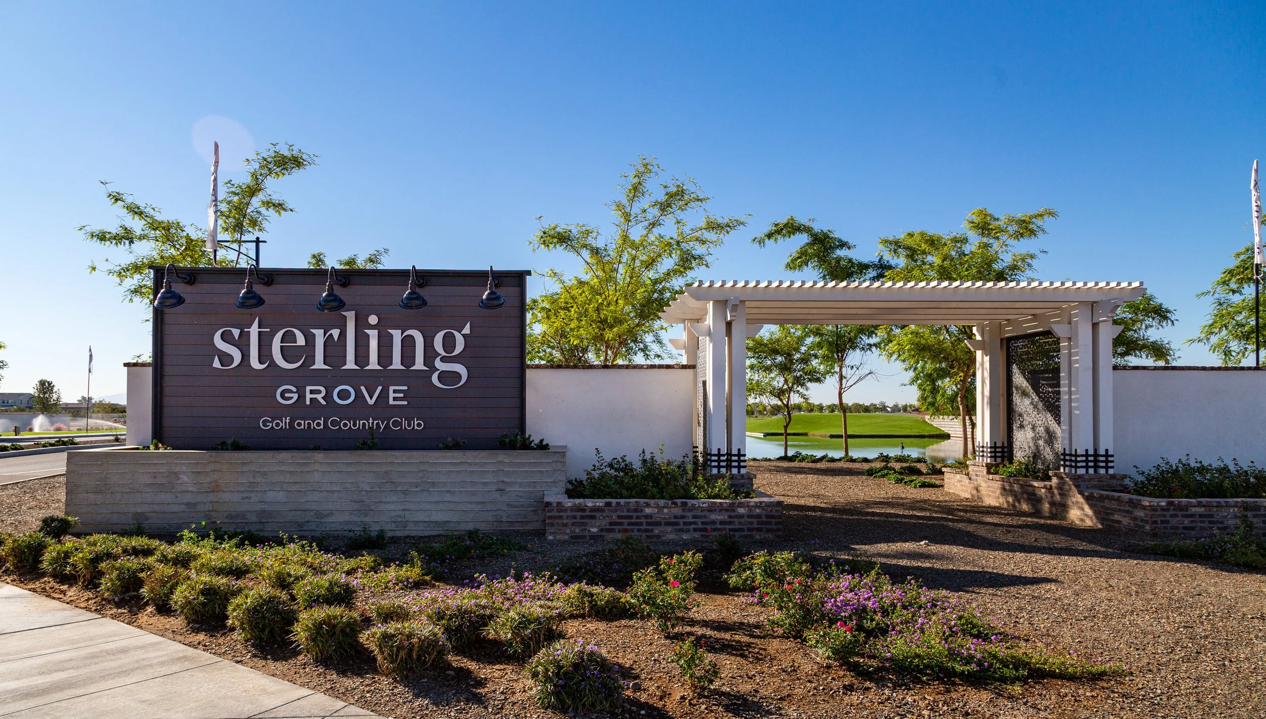 Entrance sign for Sterling Grove Golf and Country Club with landscaped garden and a white pergola.
