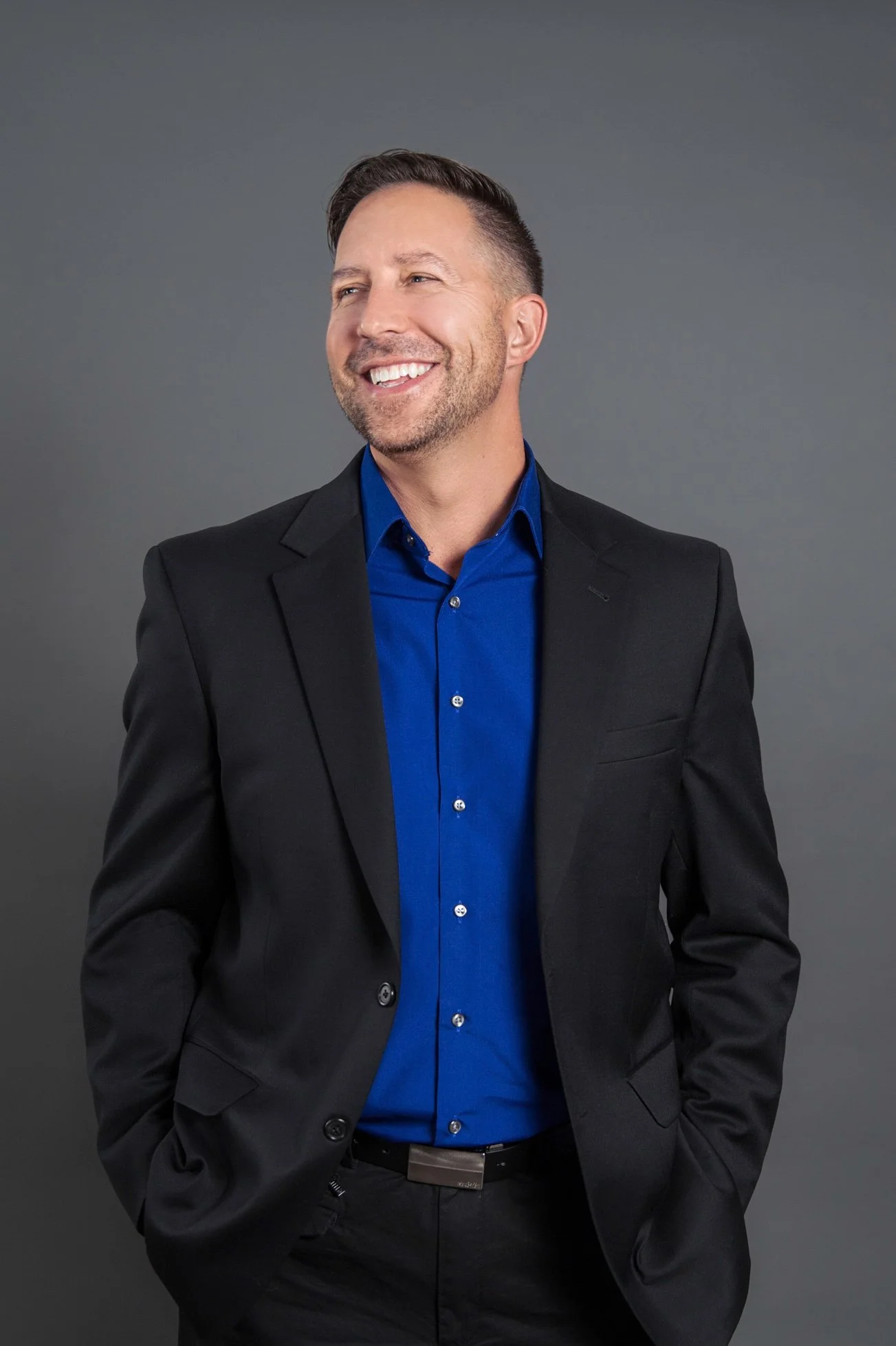 Profile photo of Greg Zehe in a suit and button-up shirt with no tie. He is smiling and looking away from the camera.