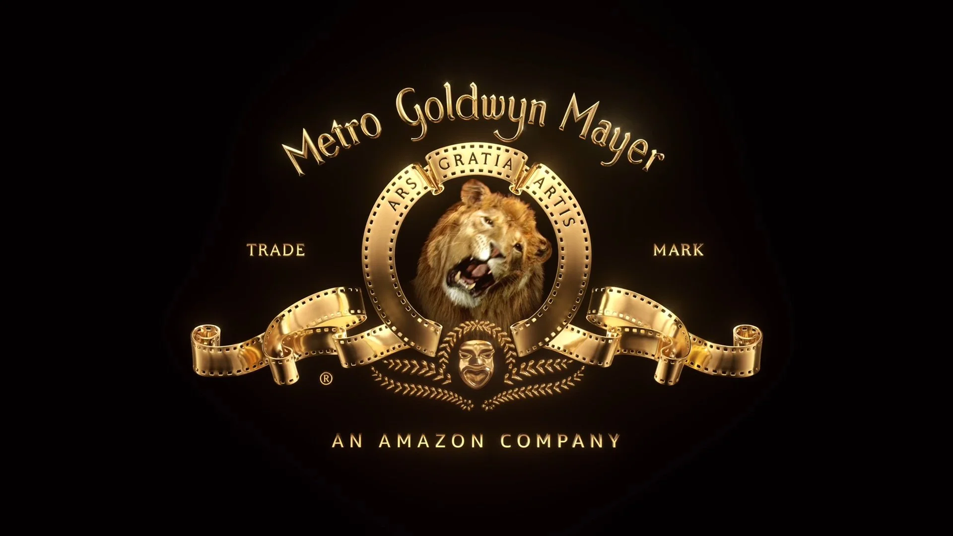 Golden logo with a lion's head at the center, surrounded by film strip borders, with the text 'Metro Goldwyn Mayer' above and 'An Amazon Company' below. The logo features a Latin phrase 'Ars Gratia Artis' and decorative elements.