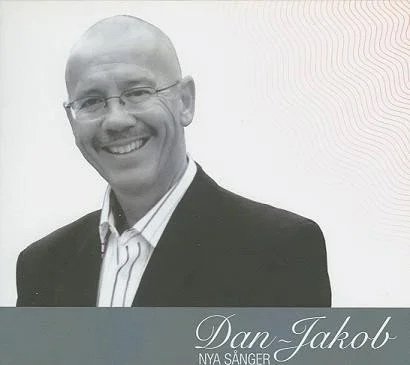 En svartvit bild av en man i kostym som ler. Text på bilden säger 'Dan-Jakob NYA SÄNGER'.