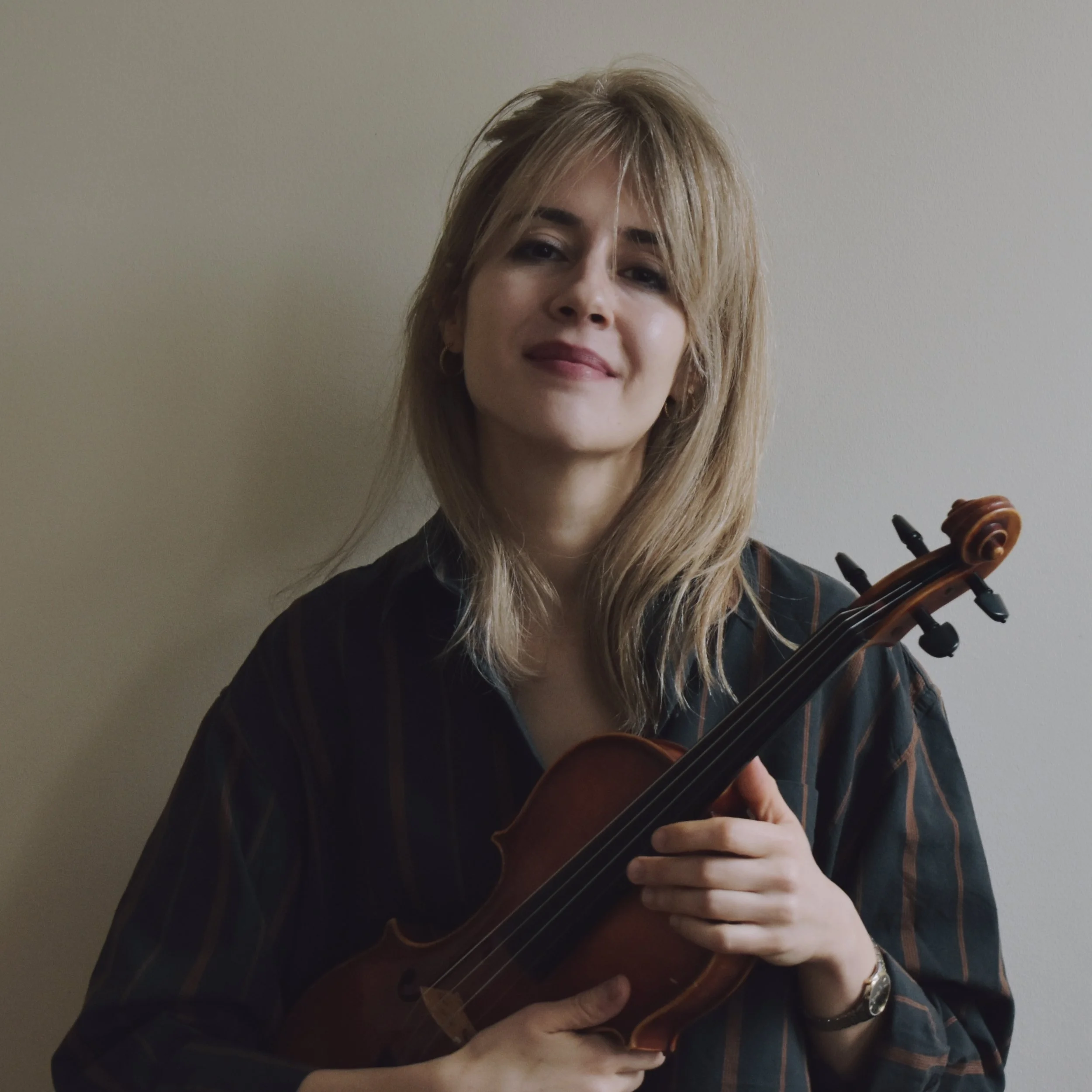 talia ramos, a female violinist posing with a smile holding her violin