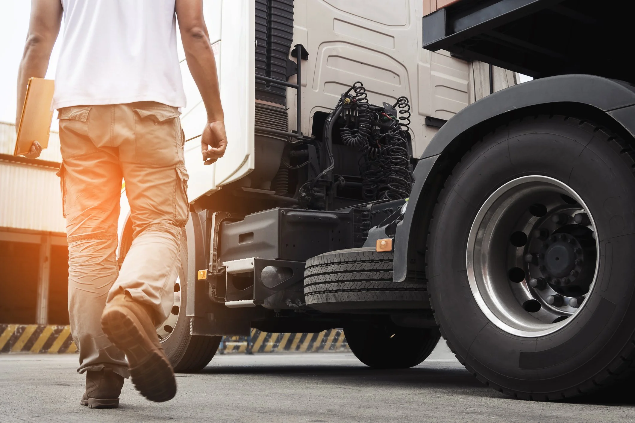 A person walking past a large semi-truck on a paved street.