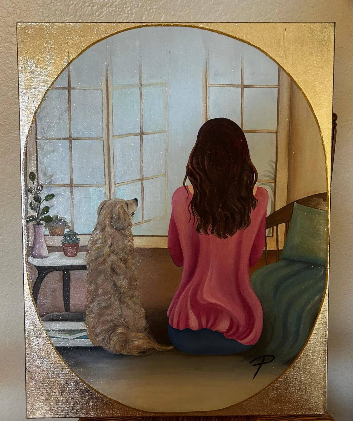 Painting of a woman with wavy brown hair wearing a pink top sitting on the floor by a green couch, looking out a large window. A golden retriever dog sits beside her, facing the window. There is a small table with potted plants near the window.