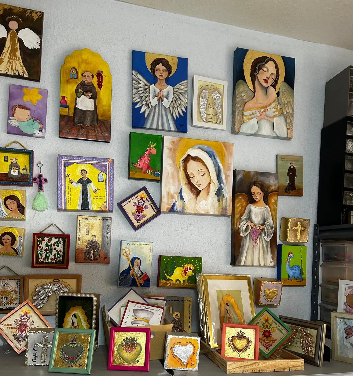A collection of religious and angel-themed artwork and decorations displayed on a wall and table.
