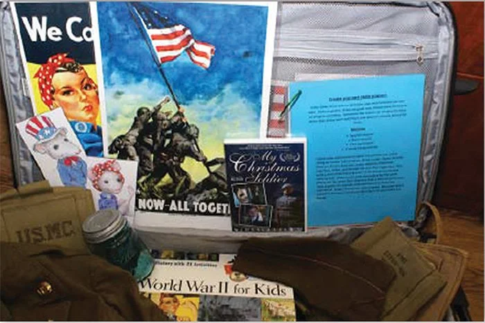 A collection of patriotic and military-themed items, including a poster of soldiers raising the American flag, a 'We Can' poster, a small flag pin, and a U.S. Marine Corps uniform, along with a blue document, a holiday card, and a book titled 'World War II for Kids'.