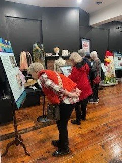 Group of elderly people examining clothing and accessories at a retail store or exhibition.
