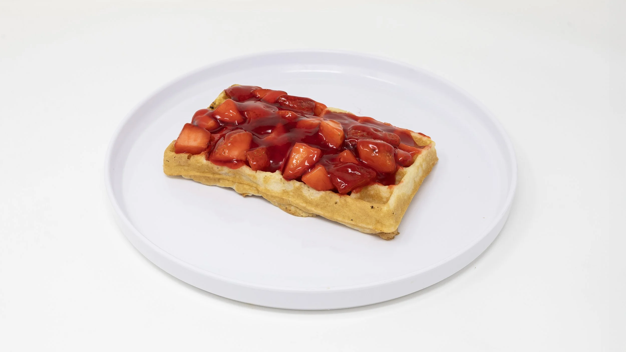 A single slice of waffle topped with strawberries and strawberry sauce on a white plate