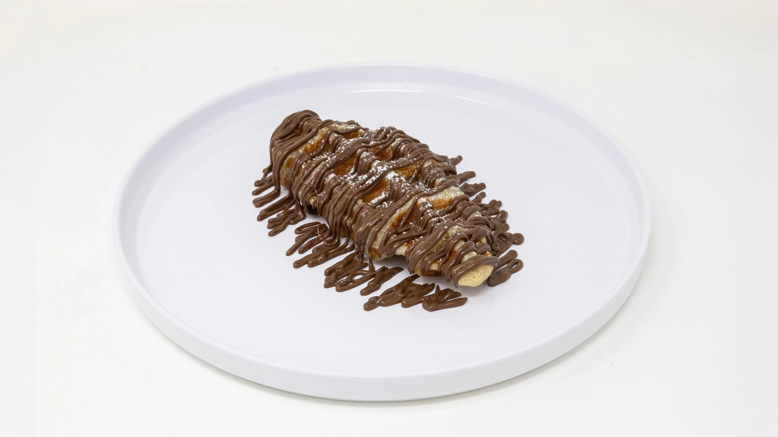 Chocolate-covered banana with drizzled chocolate on a white plate