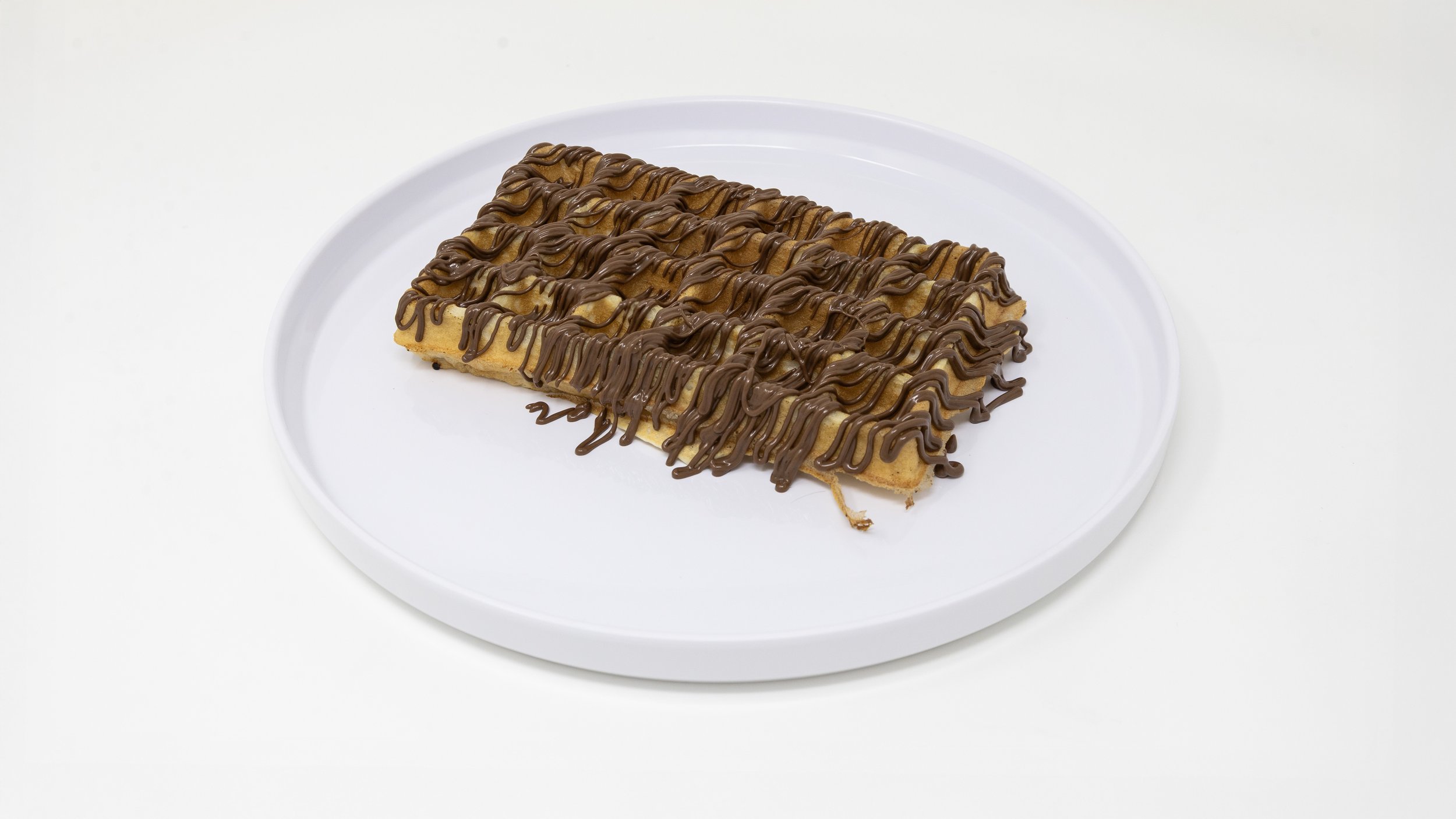 A rectangular waffle with chocolate drizzle on a white plate.