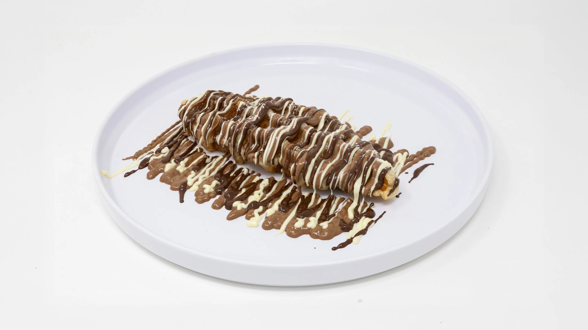 Chocolate and vanilla drizzled ice cream burrito on a white plate.