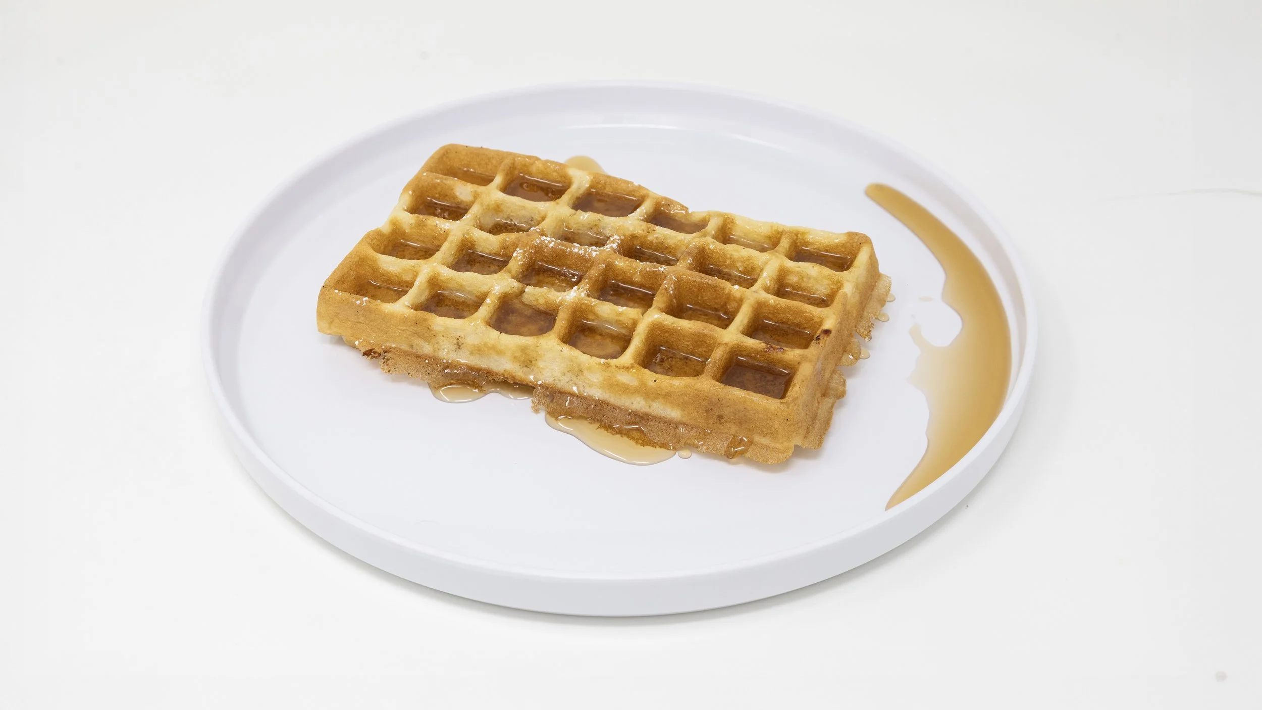 A waffle with syrup on a white plate
