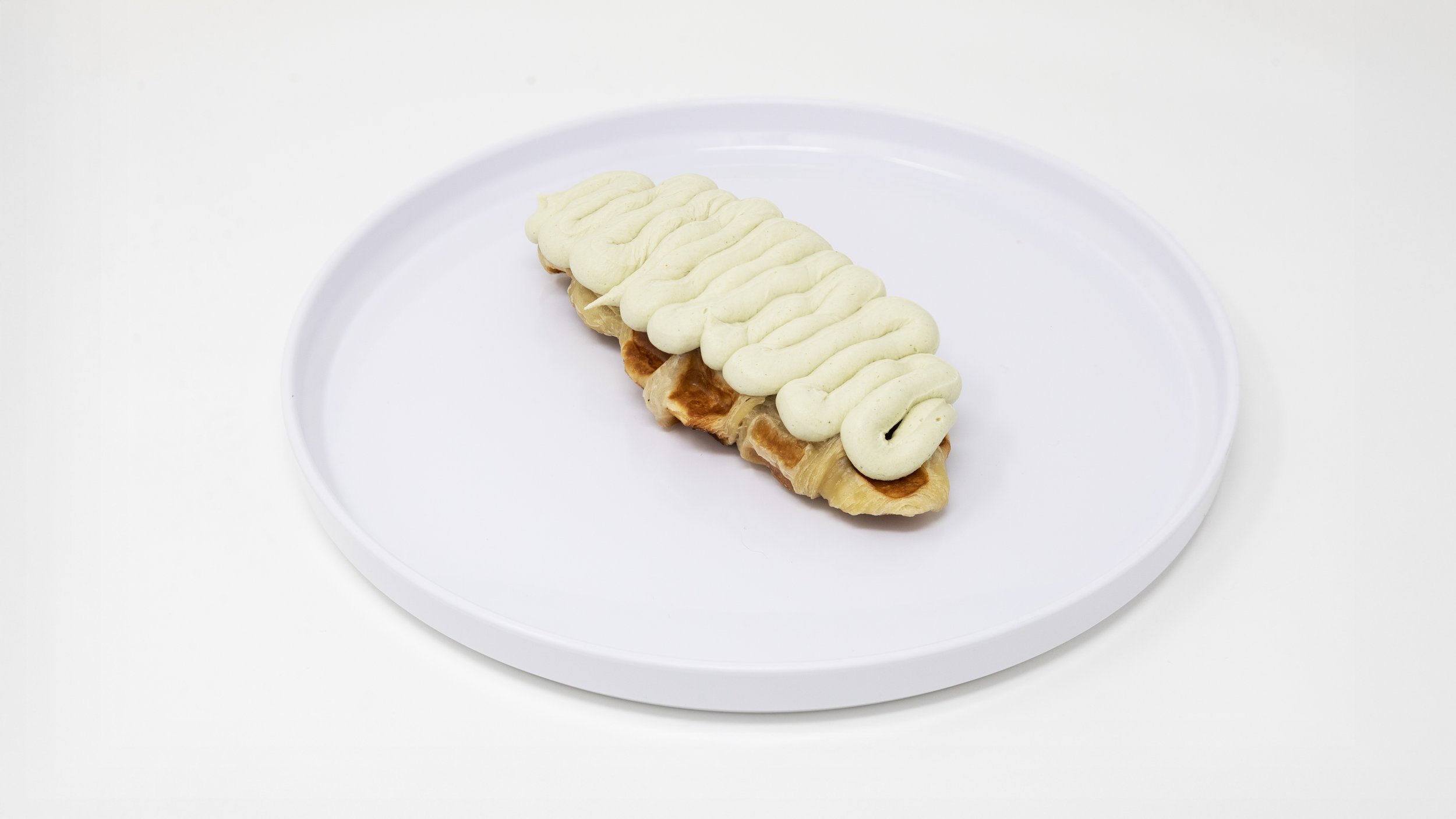 A rectangular pastry topped with crisscrossed white icing, placed on a white plate.