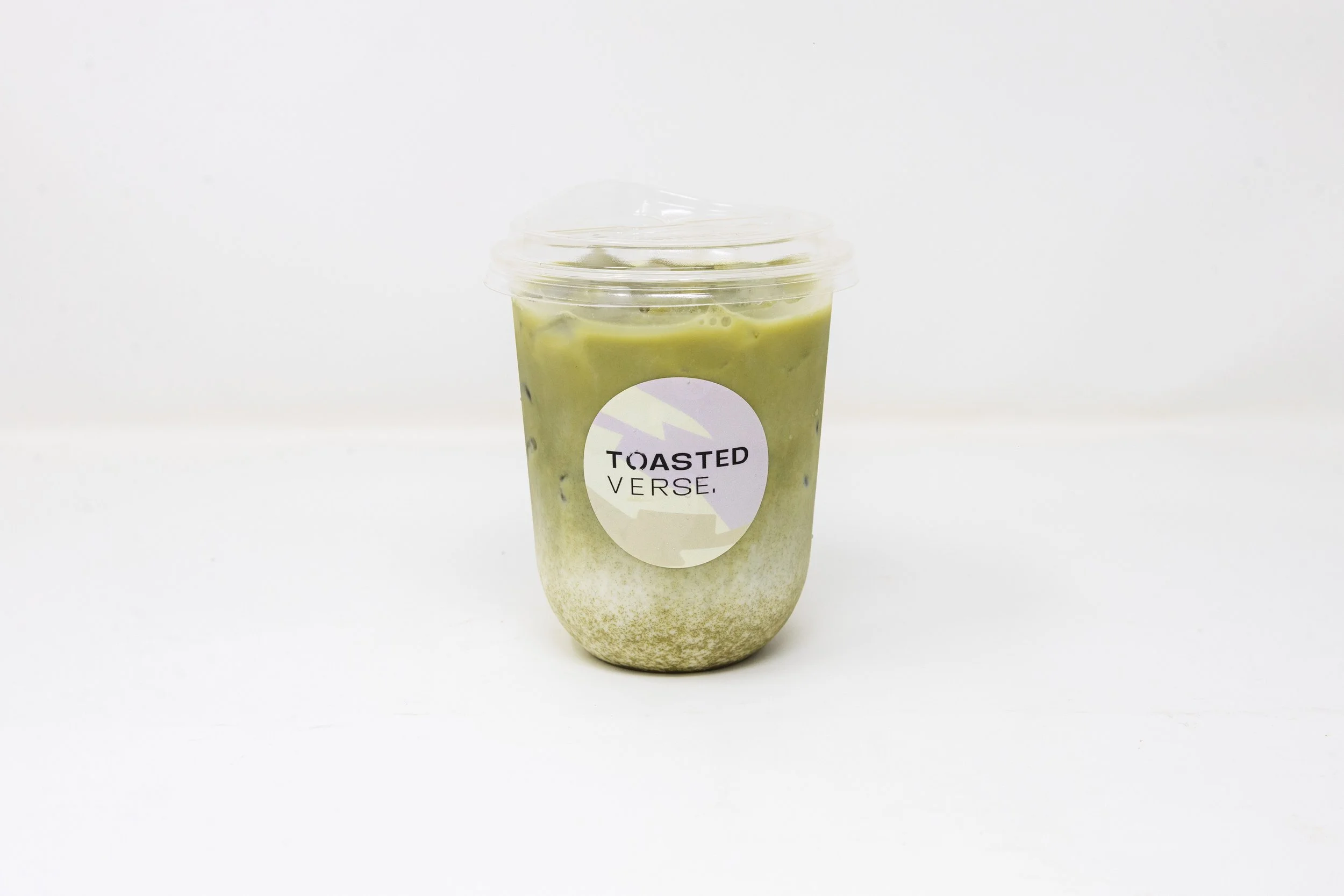 Green iced beverage in a clear plastic cup with a lid and a 'Toasted Verse' label, set against a white background.