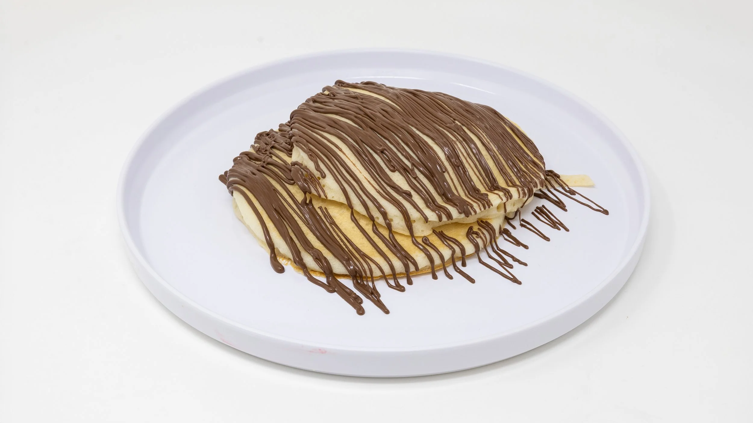 Cream-filled pastry drizzled with chocolate on a white plate.