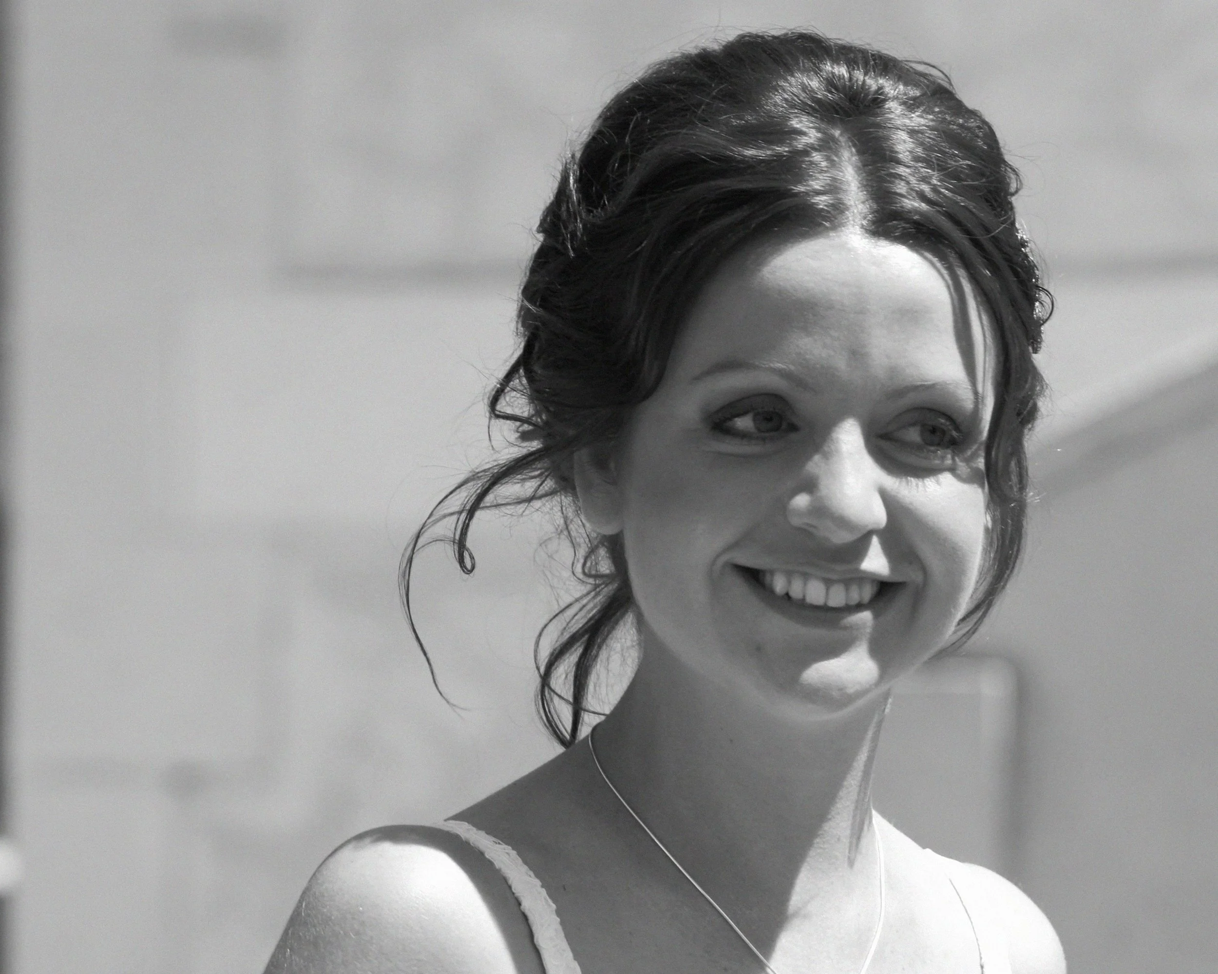 Black and white photograph of a young woman smiling, with dark hair styled in loose curls