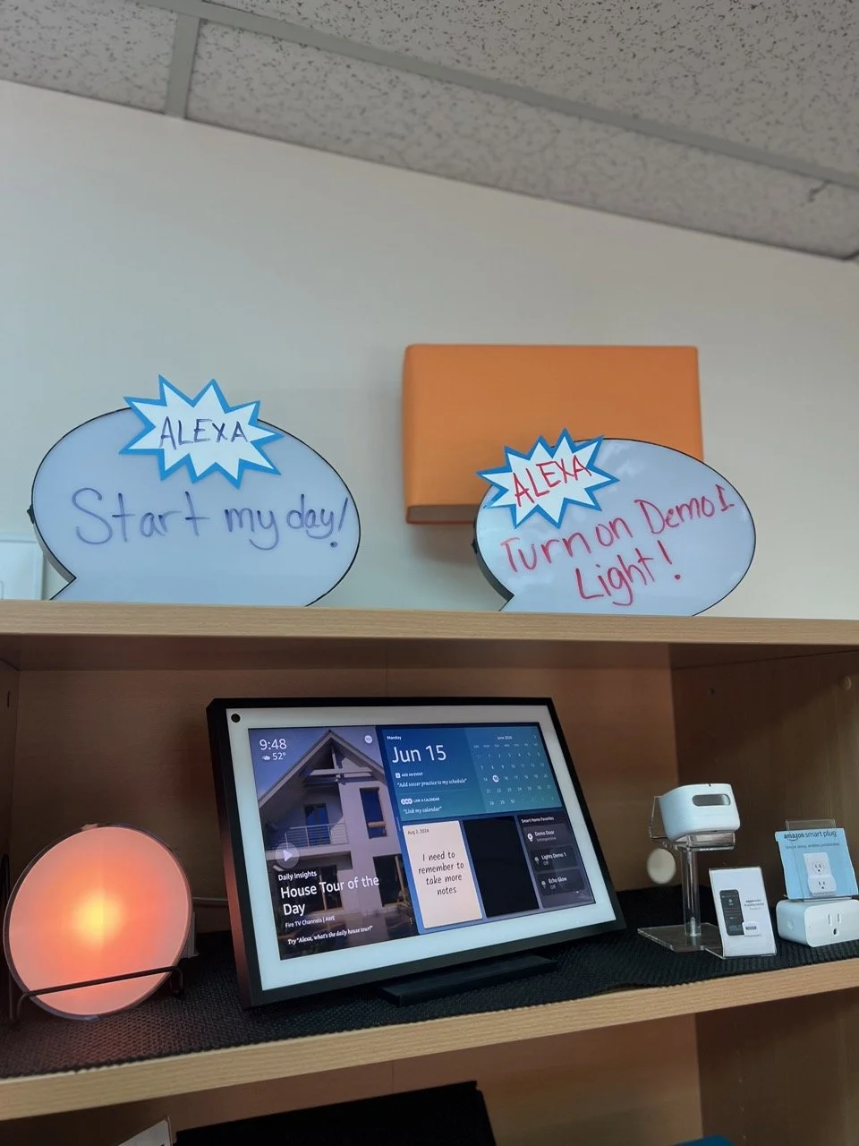 Alexas with signs that say Alexa start my day and Alexa turn on Demo 1 lights