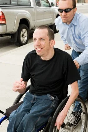 Man pushing another man in a wheelchair