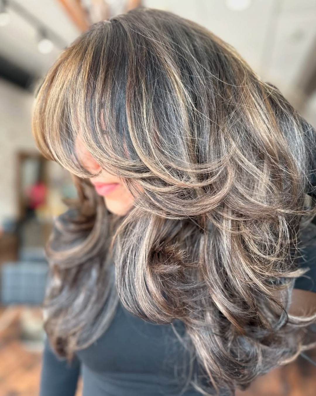 Close-up of a woman's hair with layered, styled curls in shades of gray, blonde, and brown.