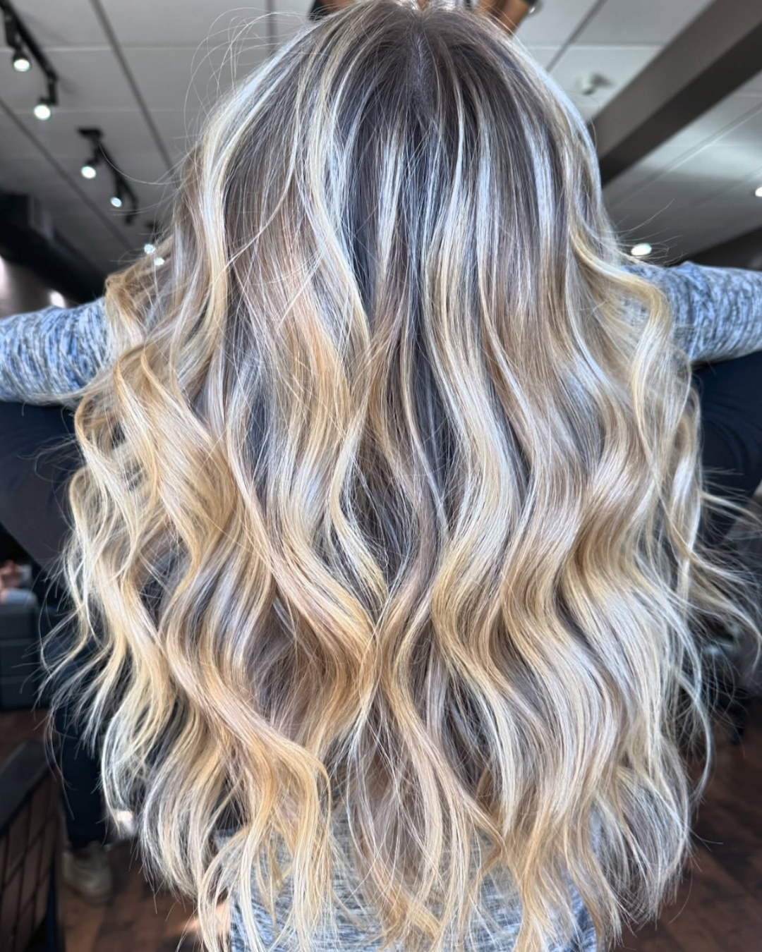 Back view of a woman with long, blonde wavy hair.