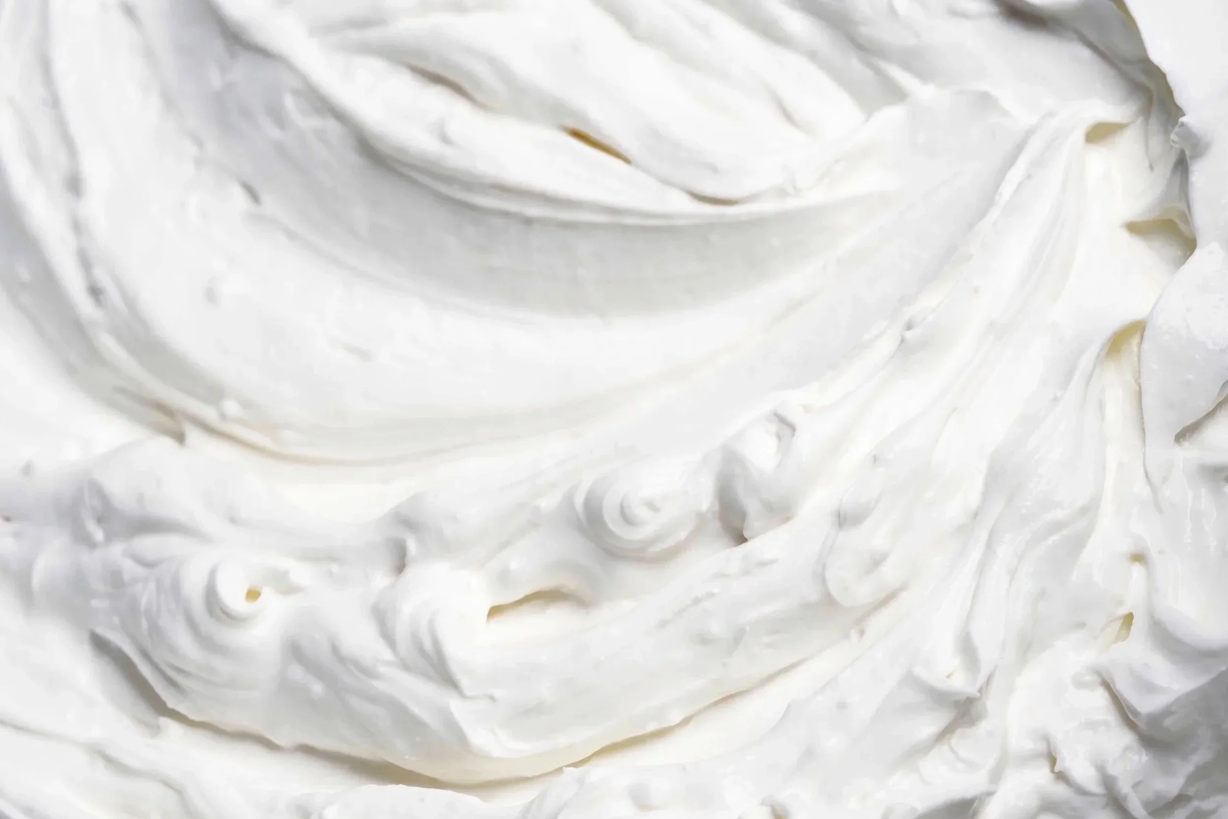 Close-up of white whipped cream or frosting with swirled texture.