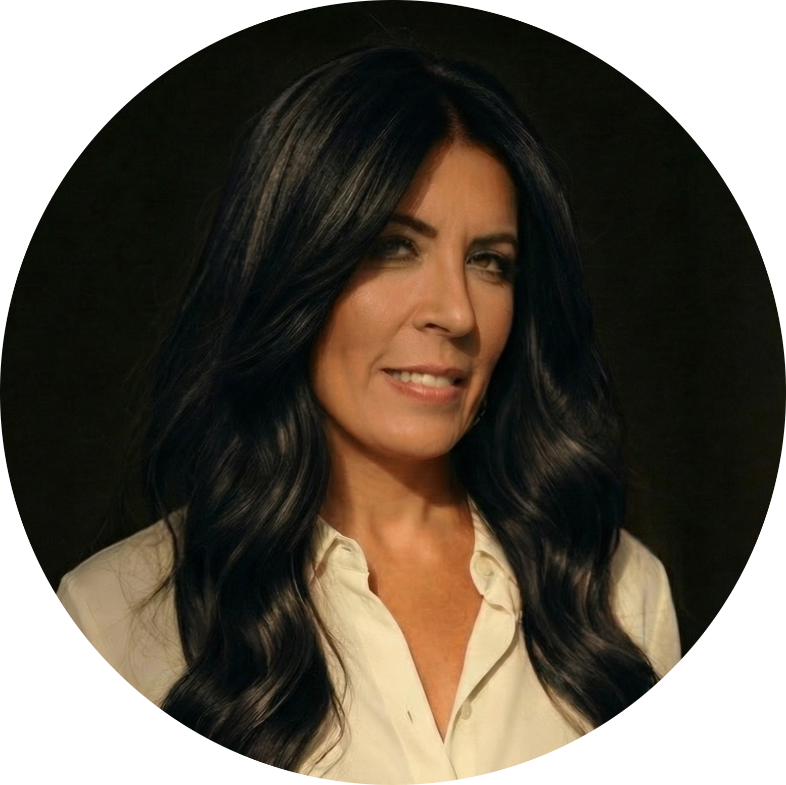 A woman with long black hair styled in loose waves, wearing a cream-colored blouse, slightly smiling against a dark background.