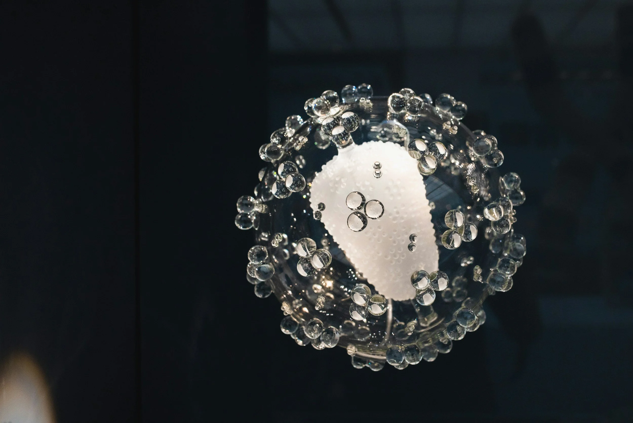 A decorative light fixture with a white oval shape at the center, surrounded by numerous small clear glass beads or orbs.