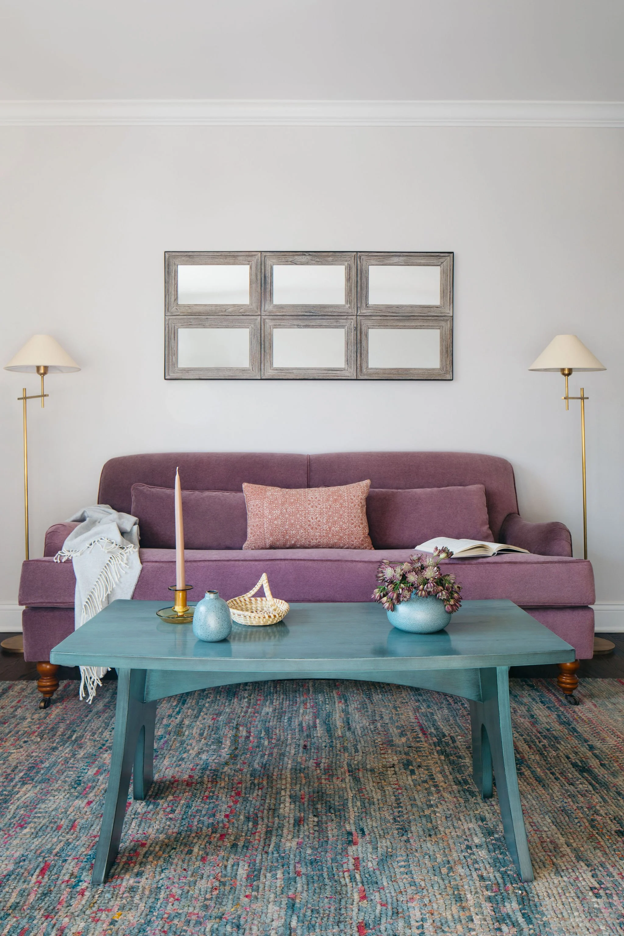 Cozy living space with purplish sofa and high end rug.