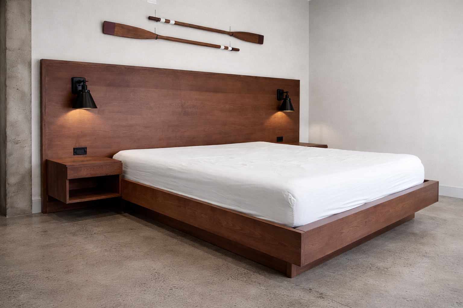 Modern bedroom with wooden bed frame, white mattress, wall-mounted black lamps, and two oars hanging above headboard.