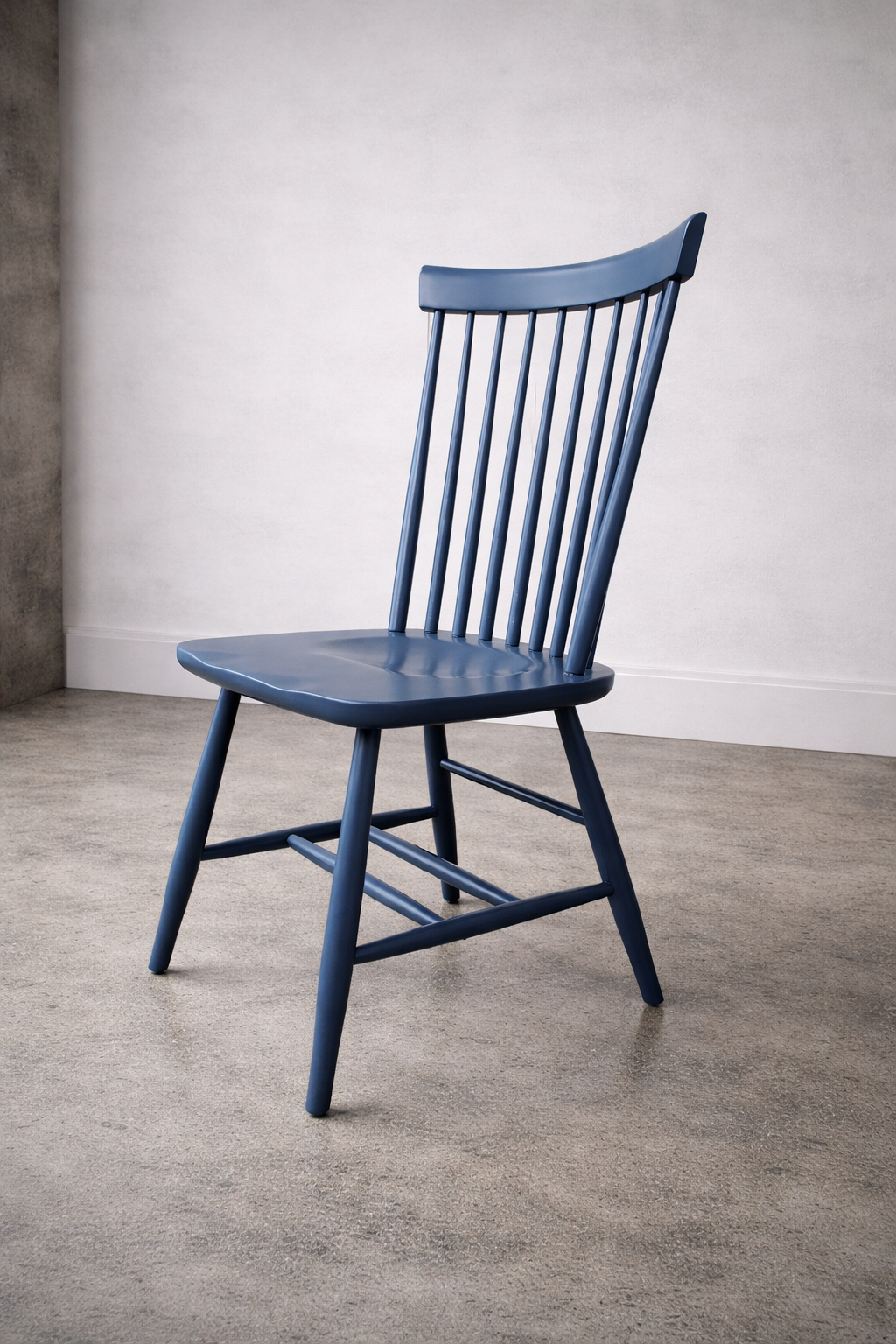 A blue wooden chair with vertical slats on the backrest, placed on a beige carpeted floor against a white wall.