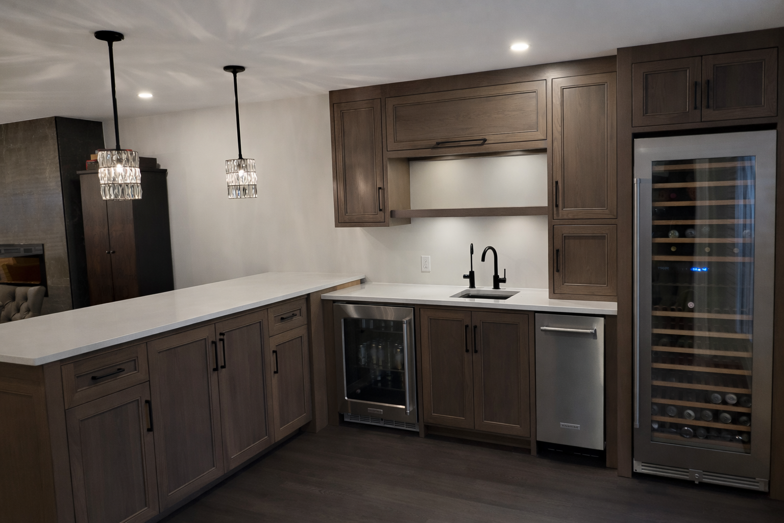 Modern kitchen with wooden cabinets, white countertop, wine fridge, and wine cooler, black sink and faucet, pendant lights, and recessed ceiling light.