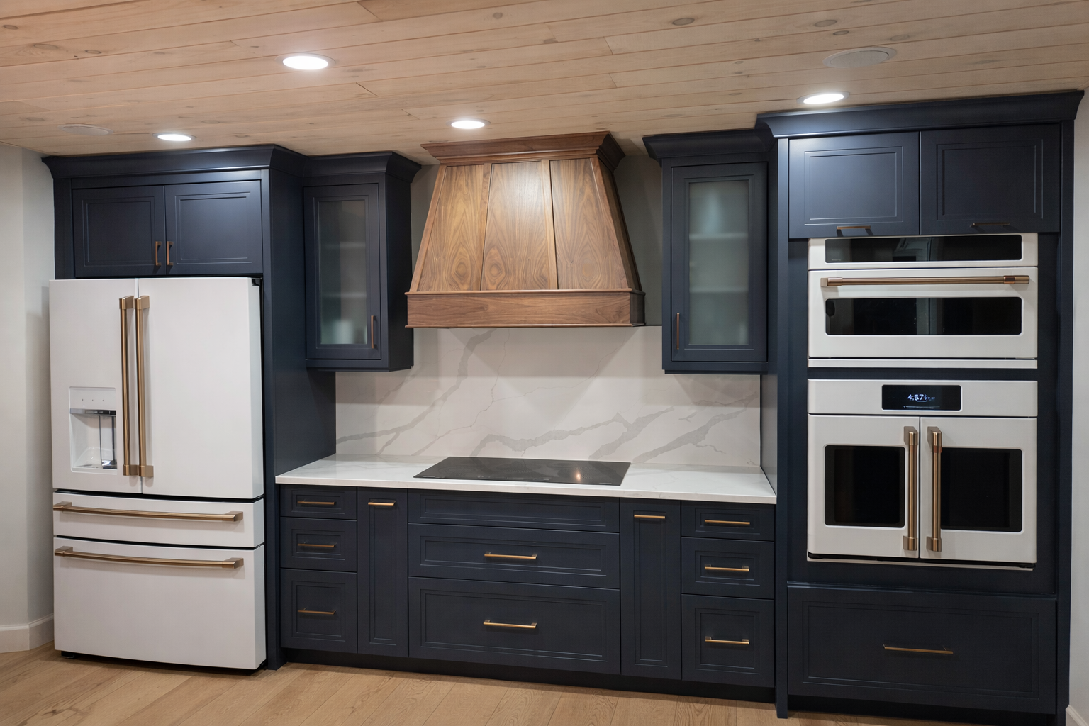 Modern kitchen with navy blue cabinets, white refrigerator, built-in oven, cooktop, and wooden range hood, white marble backsplash, and light wood flooring.