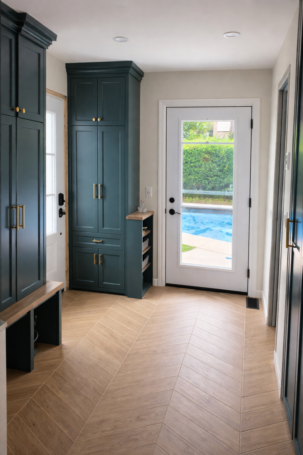 Entryway with dark teal cabinets, a white door with glass panels, and a white exterior door leading outside with a view of a backyard and pool.
