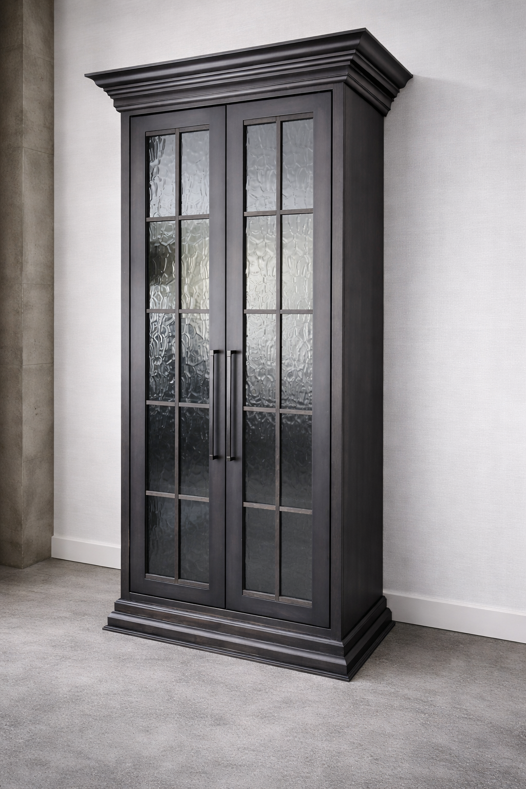 A tall black wooden cabinet with glass paneled doors and black handles, standing against a white wall in a room with light grey carpet.